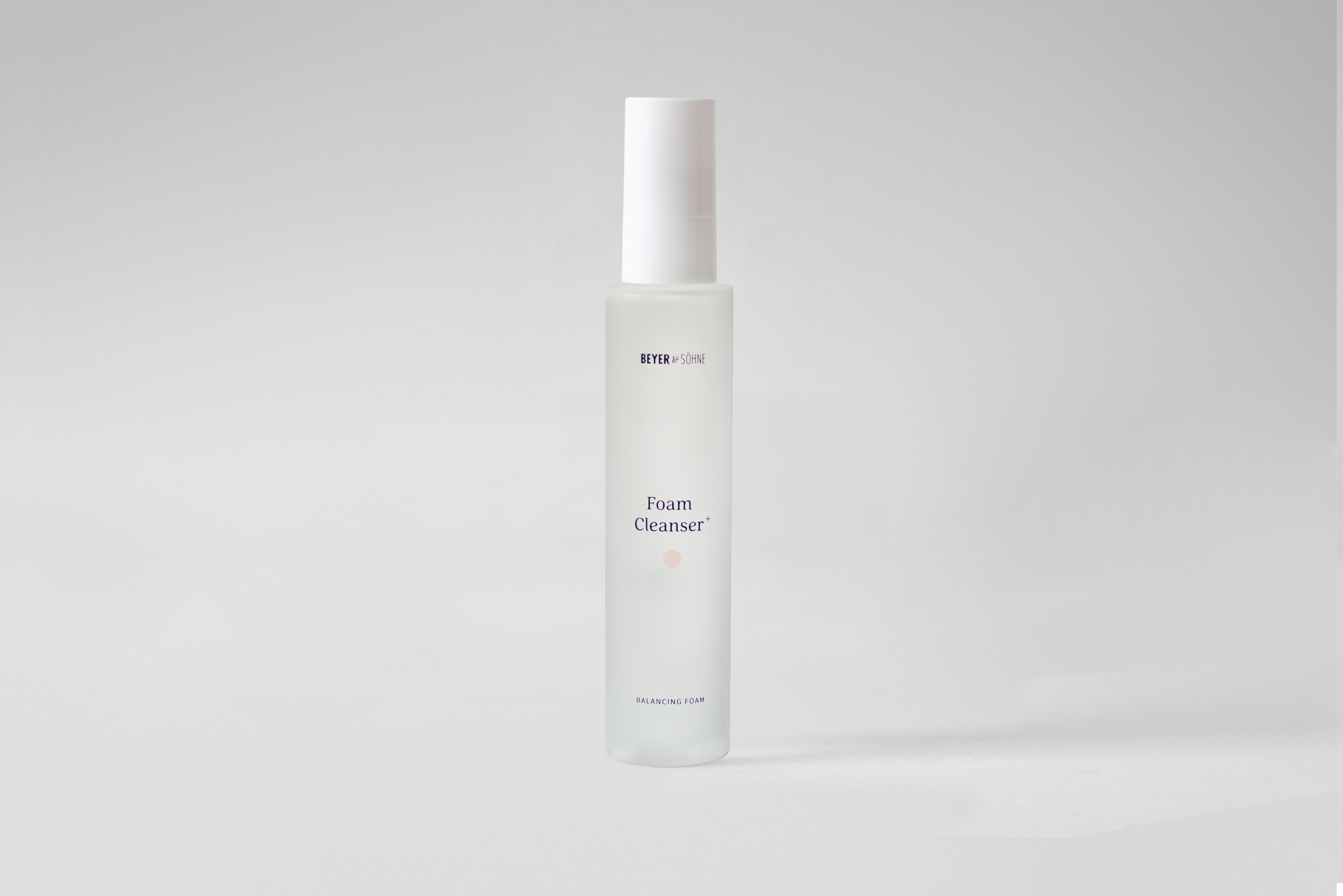 Milchig transparenter Pumpspender mit Foam Cleanser+ von Beyer & Söhne vor neutral grauem Hintergrund, klar und minimalistisch dargestellt.